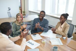 People sitting around a table in an office, clapping their hands